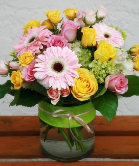 roses, gerberas and hydrangea, in delicate hues of pink, yellow and green - all dressed up with ribbon and raffia.
