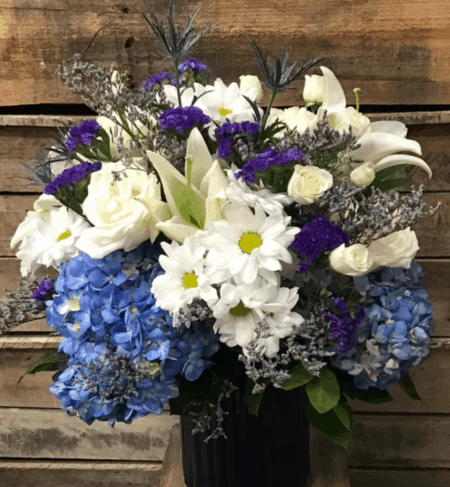Stunning and simply beautiful in blue. White lilies, daisies, roses and spray roses are accented with blue hydrangea, filler and crisp blue vase. A perfect gift for many occasions. 