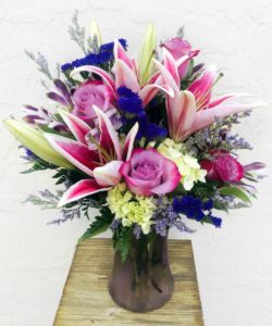 pink and white lilies with pink and purple floral accents in vase