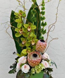 green orchids with blue and pink pastel floral accents in vase