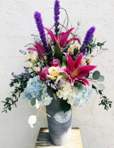 Vibrant pink lilies, popping purple liatris, soft blue hydrangea, peach and lavender roses and wispy purple caspia stand tall in this keepsake galvanized metal bucket.