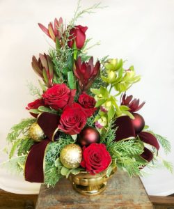 Regal red roses and orchids accented with burgundy and gold accessories.