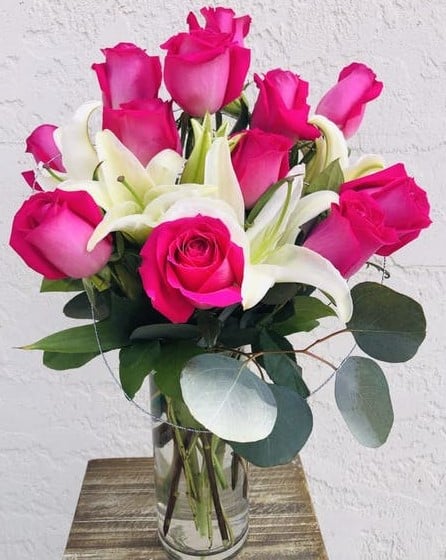 An arrangement of pink roses and white lilies smell amazing and will surely put a smile on anyone's face. The vase is a tall cube shaped glass container, that's accented with black river rock on the bottom and greenery decor to make this gift simply gorgeous!!