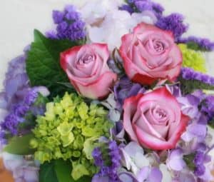 Send a bright colored arrangement full of lavender and purples! Designed elegantly in a cube glass container, sits hydrangeas of various bright colors, lavender roses and purple statice.