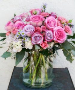  amazing pink and purple pastel colored roses are filled with hydrangeas and other elegant greenery