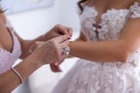 Woman putting bracelet on bride
